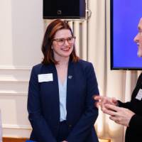 Laura Aikens smiles while speaking with two alumni